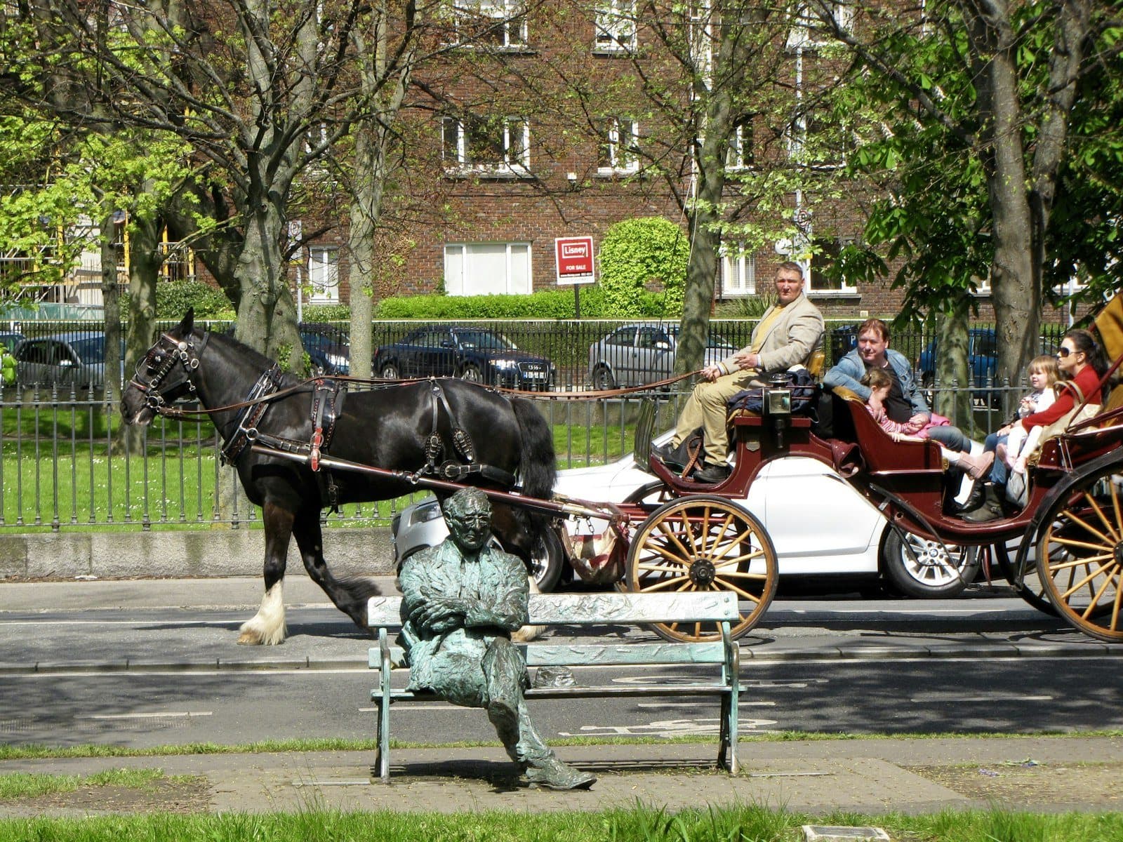 Horse-drawn carriage passing the Patrick Kavanagh statue by the Grand Canal, Dublin